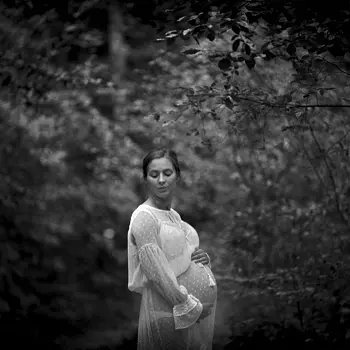 Kobieta w ciąży na tle liściastego lasu